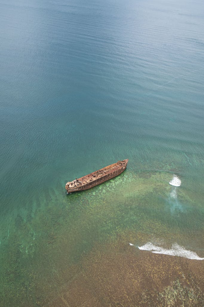 A stunning aerial shot of an old shipwreck in the turquoise waters off Hawaii, showcasing vibrant aquatic hues.