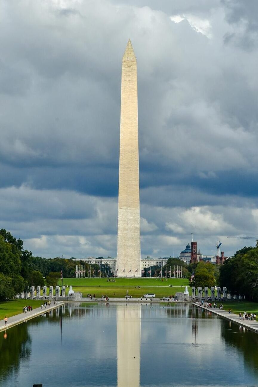A stunning view of the Washington Monument with water reflection under a cloudy sky.