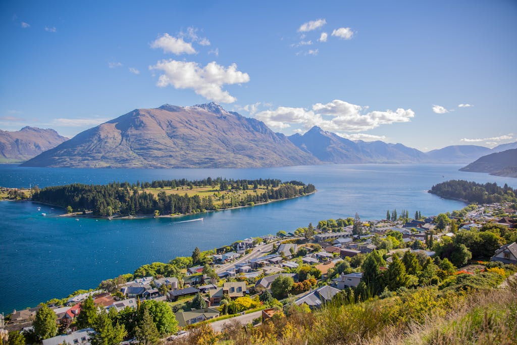 Breathtaking aerial view of Queenstown by Lake Wakatipu, surrounded by majestic mountains under clear skies.