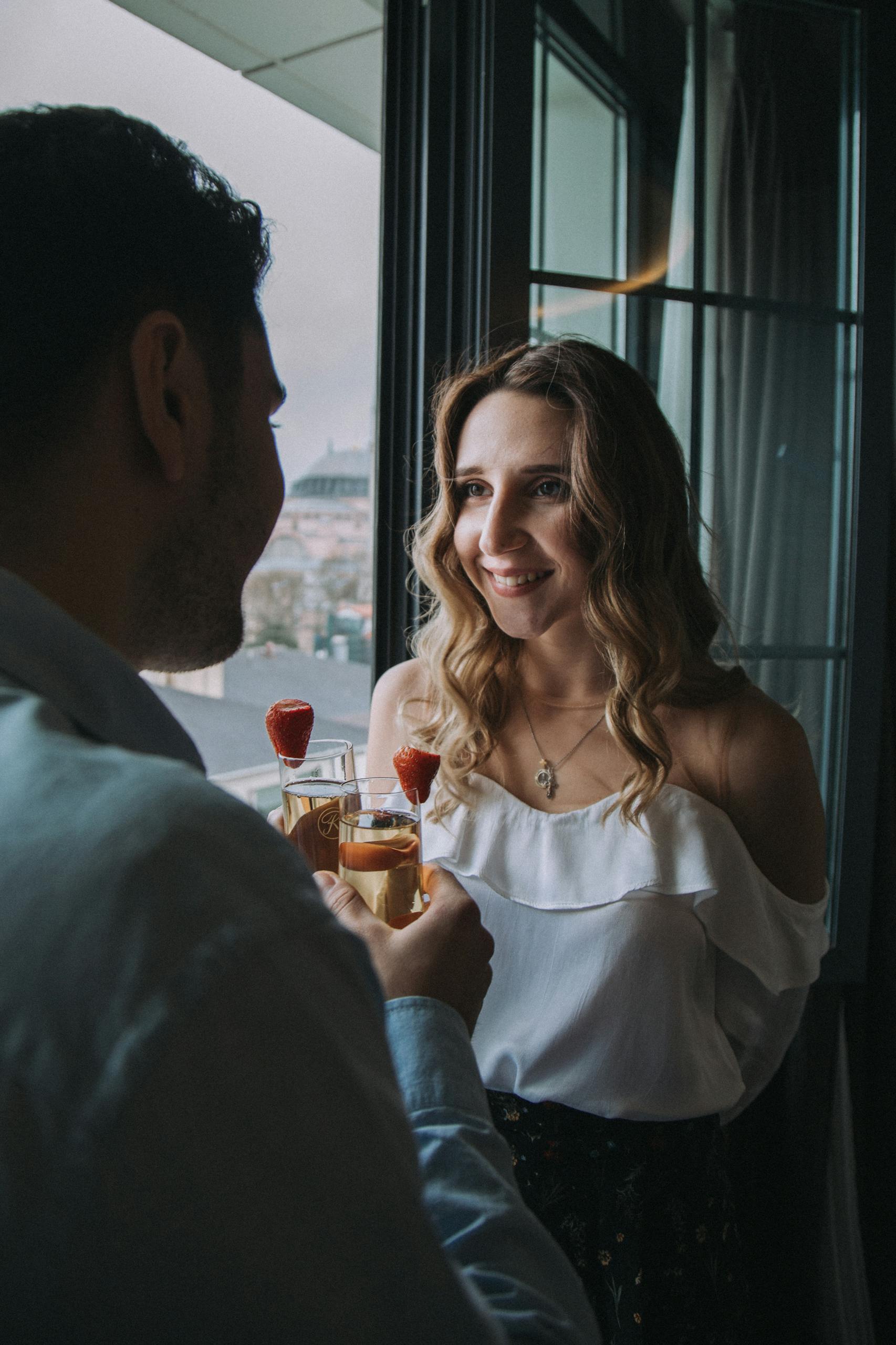 A young couple enjoying cocktails together in a romantic setting by a window.