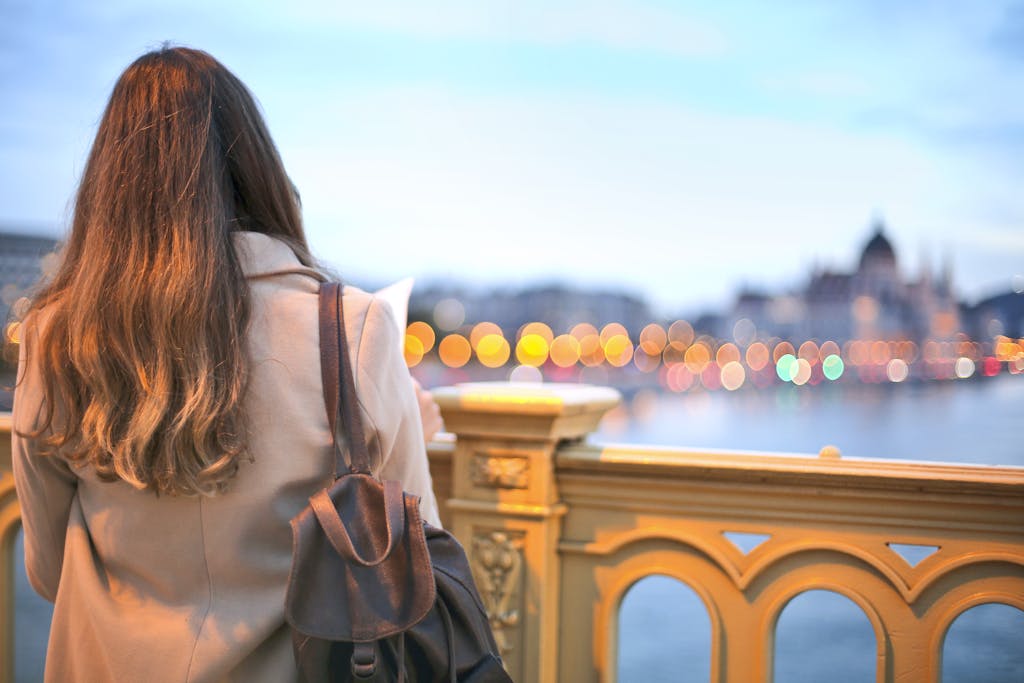 A woman enjoys a scenic view of Budapest's Danube River with bokeh lights in the background.
