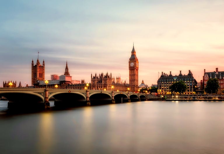 Scenic view of Big Ben and Westminster Bridge over the Thames River at sunset in London, UK.