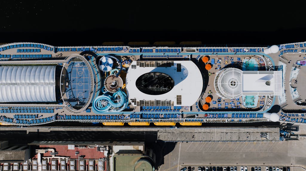 A luxurious cruise ship docked in Napoli, Italy, showcasing pools and leisure areas from above.