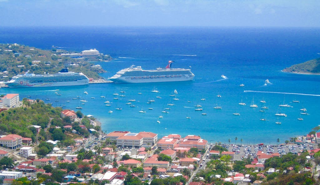 Scenic aerial view of a tropical harbor with cruise ships and sailboats in clear blue waters.