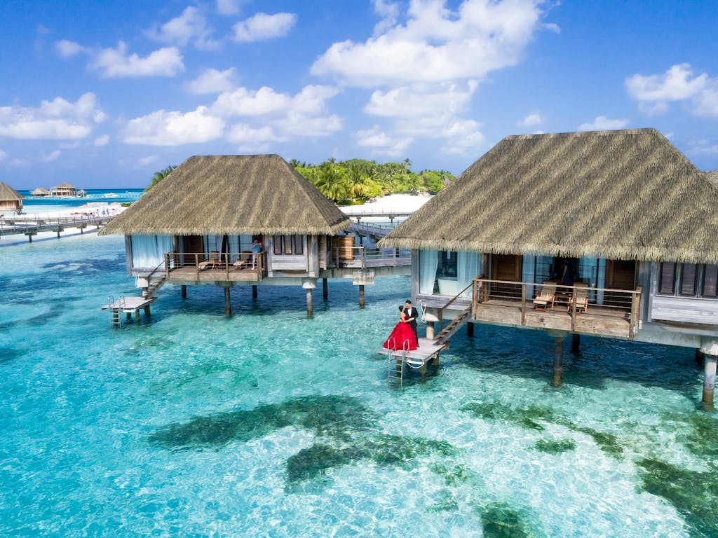 A scenic view of overwater bungalows and a couple enjoying a tropical paradise in the Maldives.