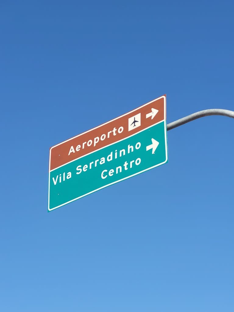 Directional street sign pointing to airport and city center under a clear blue sky.