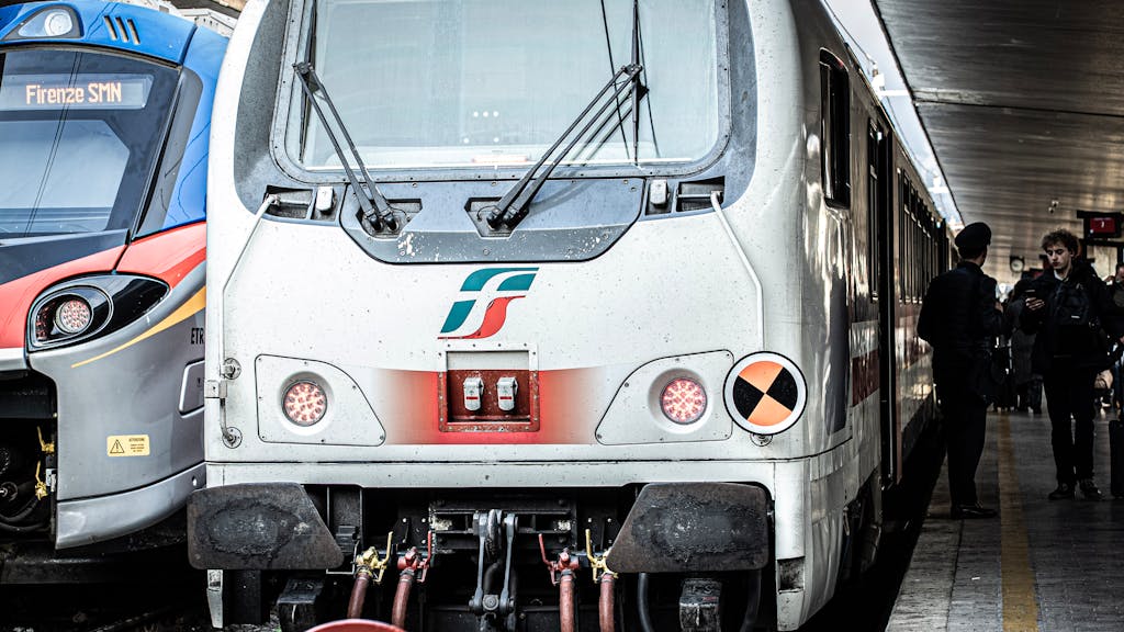 Front view of trains at Florence SMN station with passengers nearby.