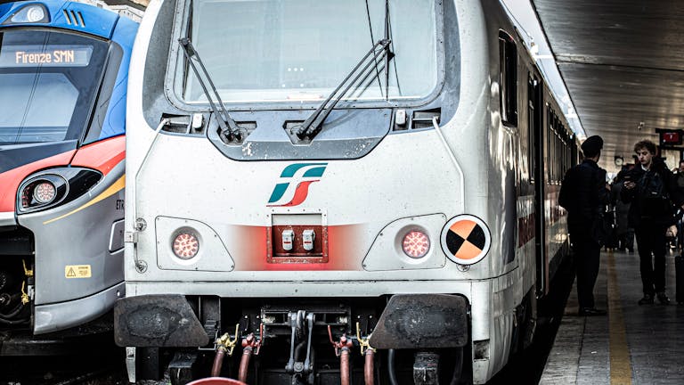Front view of trains at Florence SMN station with passengers nearby.
