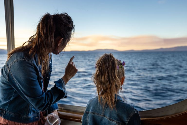 A mother and daughter share a moment while enjoying a scenic boat ride at sunset.